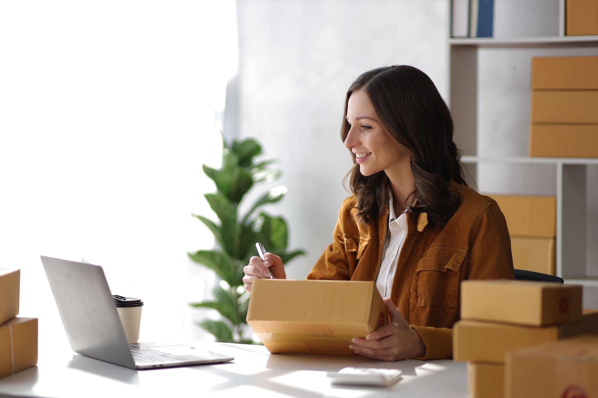 Female entrepreneur starting a small business for online sales working with parcel boxes at home checking orders from the internet preparing for delivery.